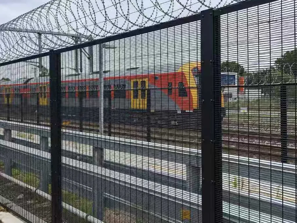 Black 358 fence with razor wire topping beside a railway