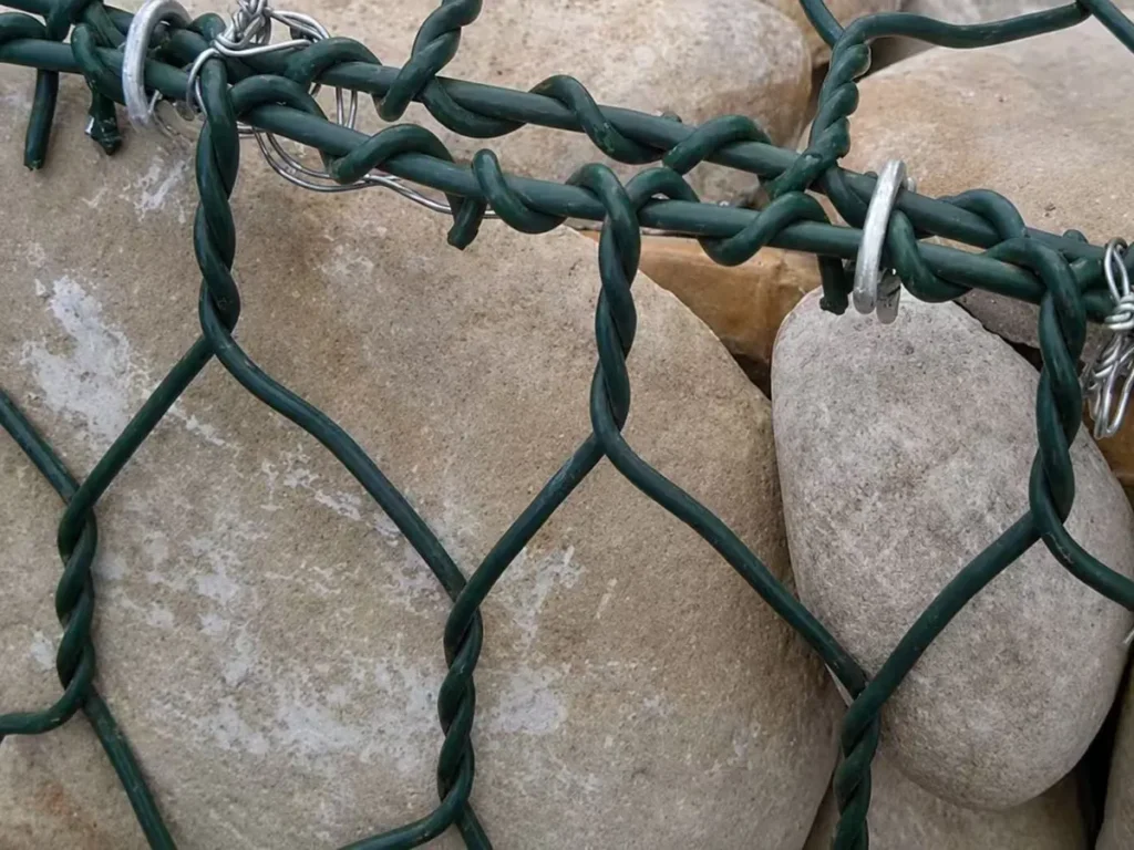 Green PVC-coated gabion panels joined with lacing wire and steel rings