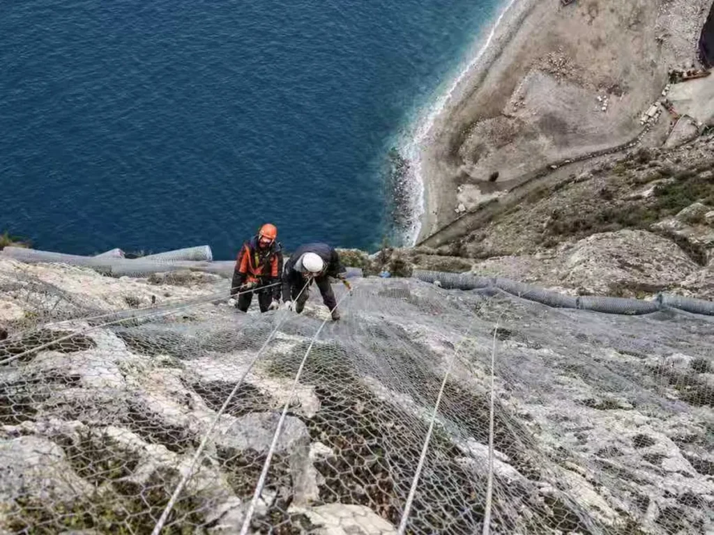 Hexagonal mesh draped over a cliff face for rockfall protection