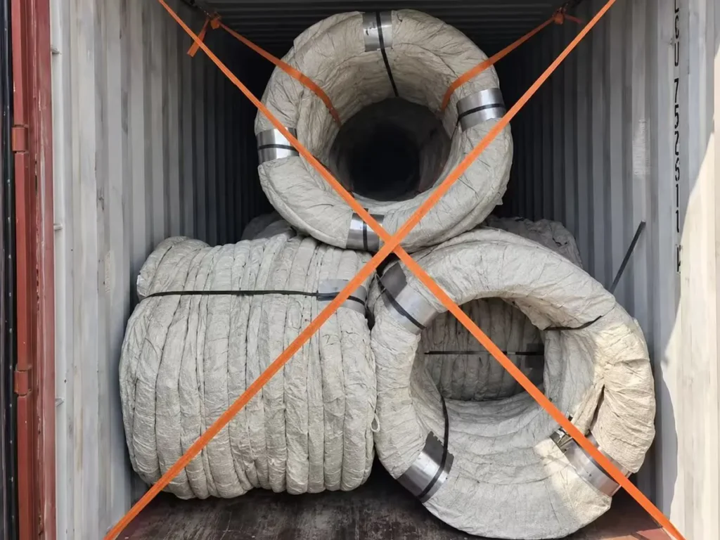 Razor wire coils wrapped in woven bags and strapped in a container